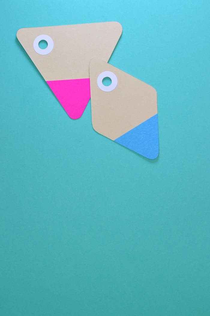 Two colorful paper tags with holes on a teal background. Ideal for design and marketing concepts.